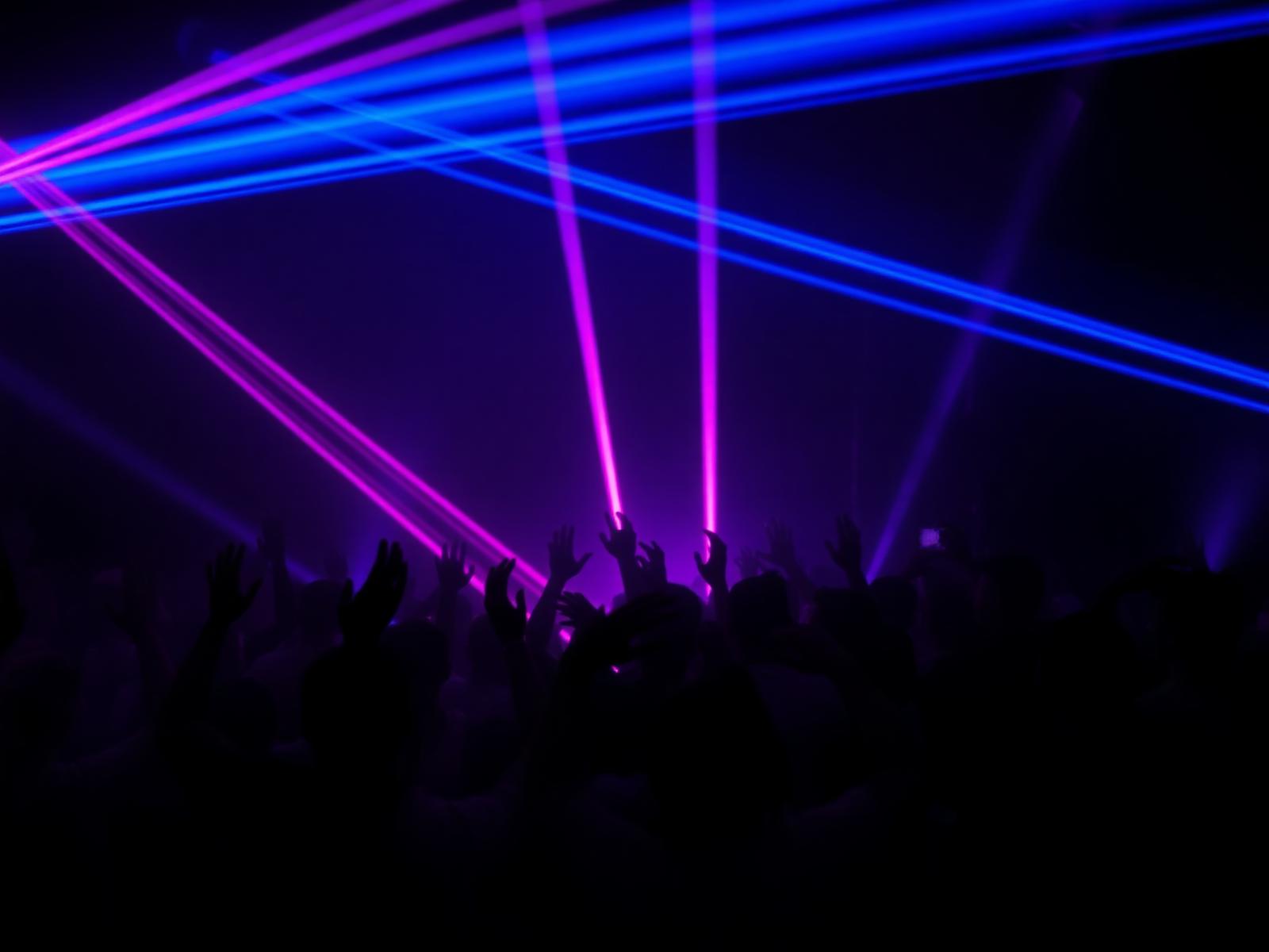 Neon nightclub crowd bathed in pink and blue lasers